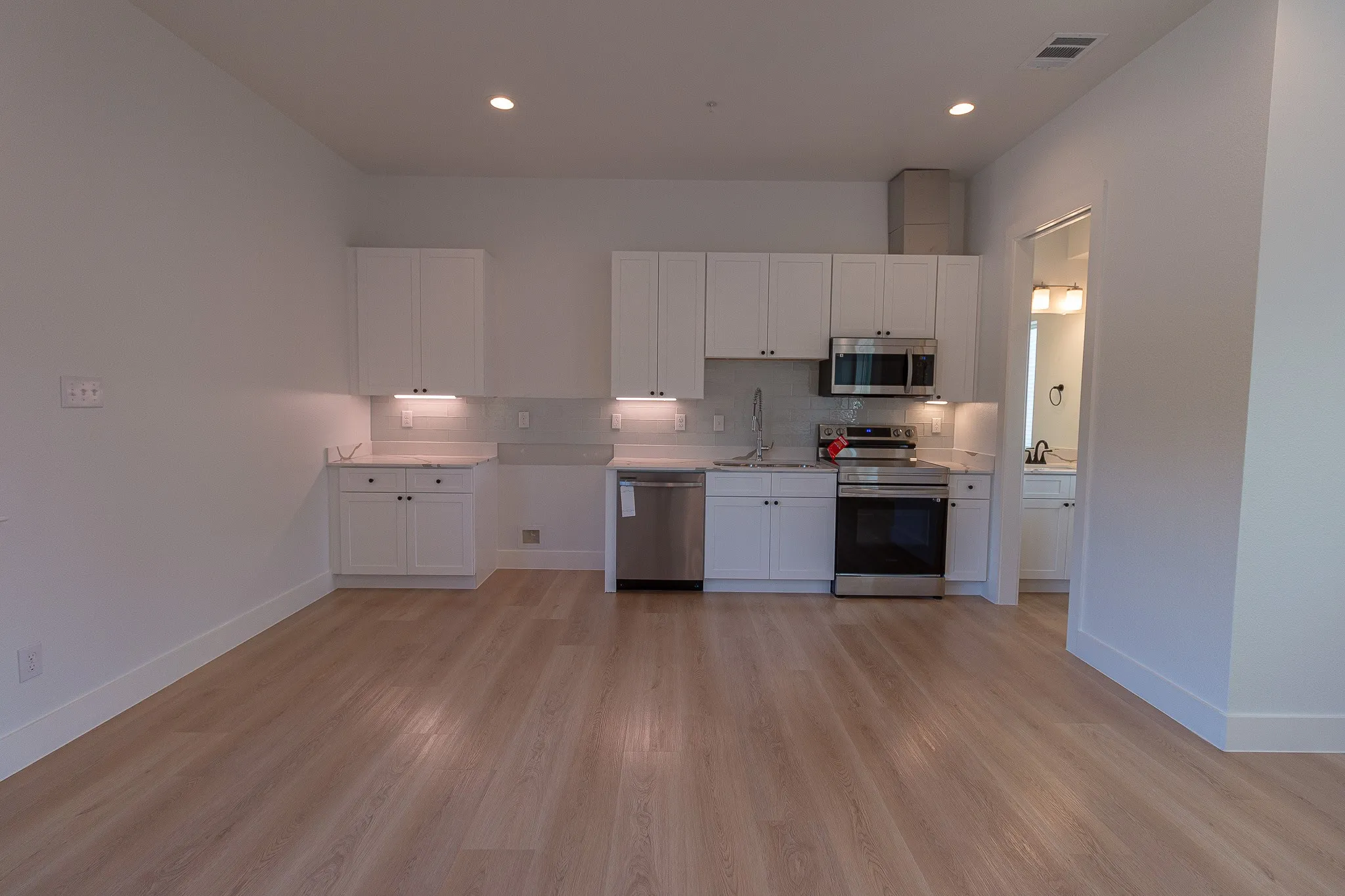 Kitchen featuring backsplash, white cabinets, sink, light hardwood / wood-style flooring, and appliances with stainless steel finishes