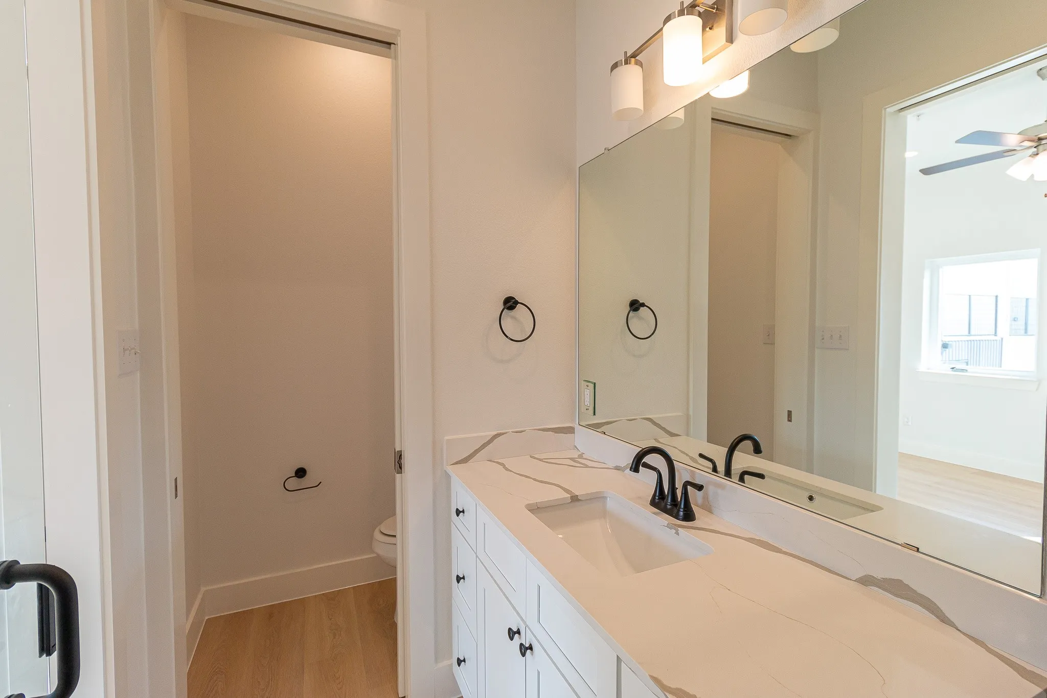 Bathroom with ceiling fan, toilet, wood-type flooring, and vanity