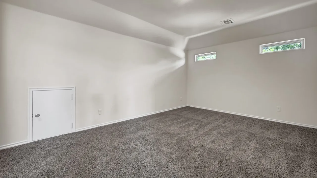 Recessed lighting illuminates this carpeted room, featuring white walls and high-set windows