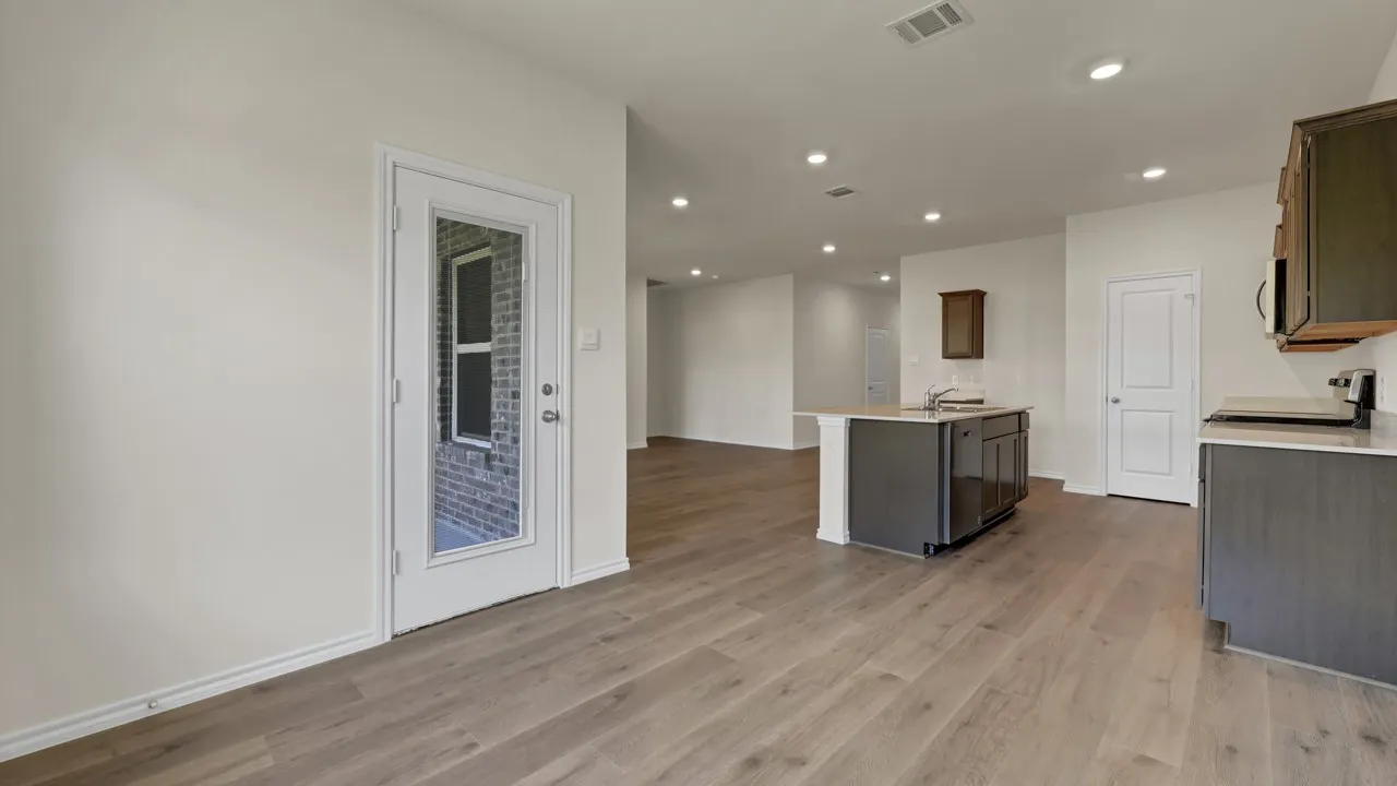 Open-concept living space featuring wood-finish flooring, recessed lighting, and a kitchen island with an undermount sink