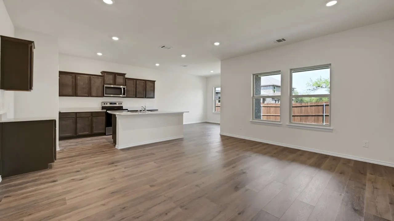 Open-concept living space with wood-finish flooring, recessed lighting, and a kitchen featuring dark cabinetry and a central island