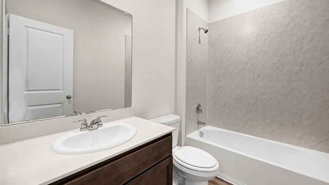 Dark wood-finish vanity with an integrated oval sink, chrome-finish faucet, and a spacious wall-mounted mirror