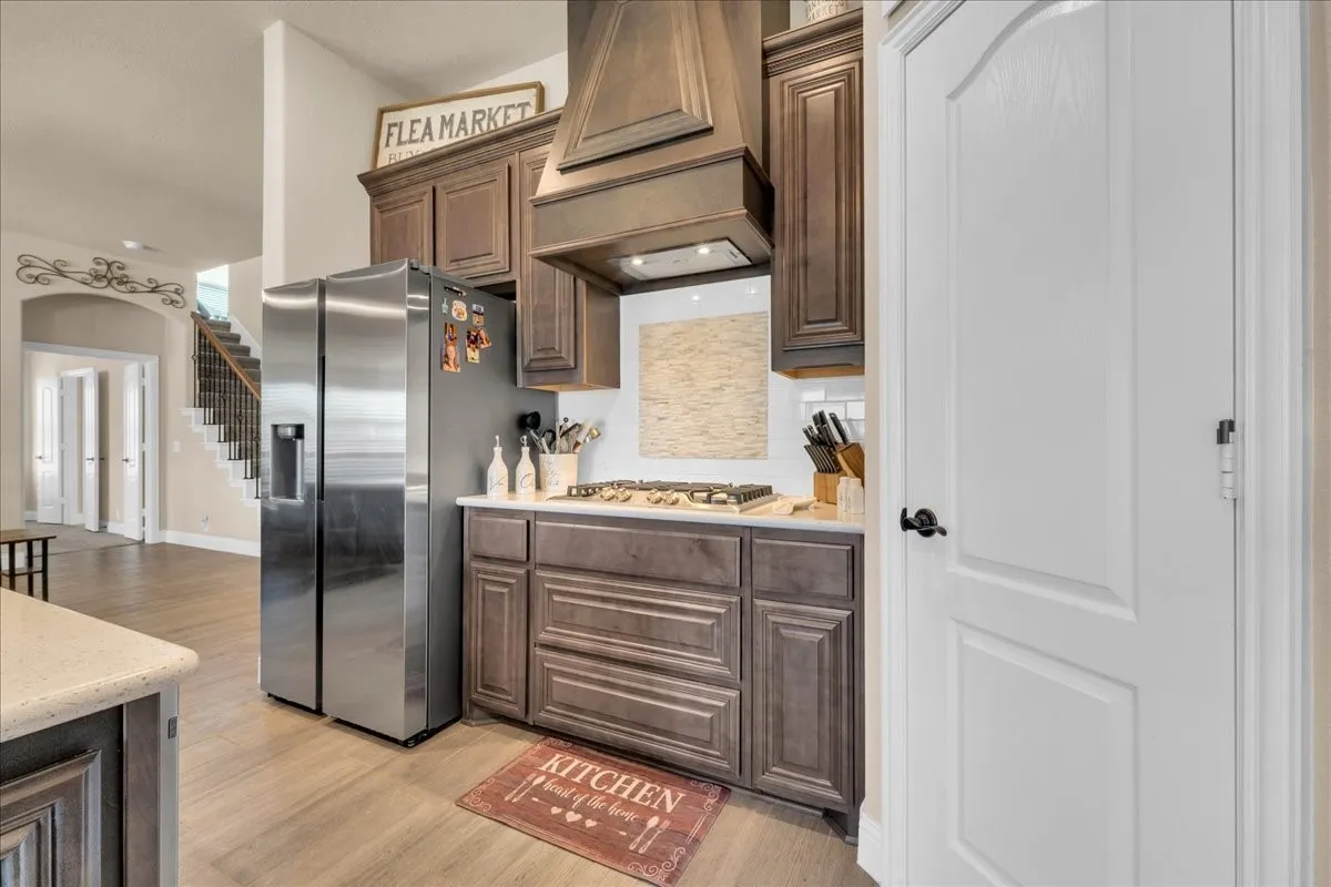 Kitchen featuring wood-finish flooring, dark wood cabinetry, white countertops, and a gas range with a decorative range hood