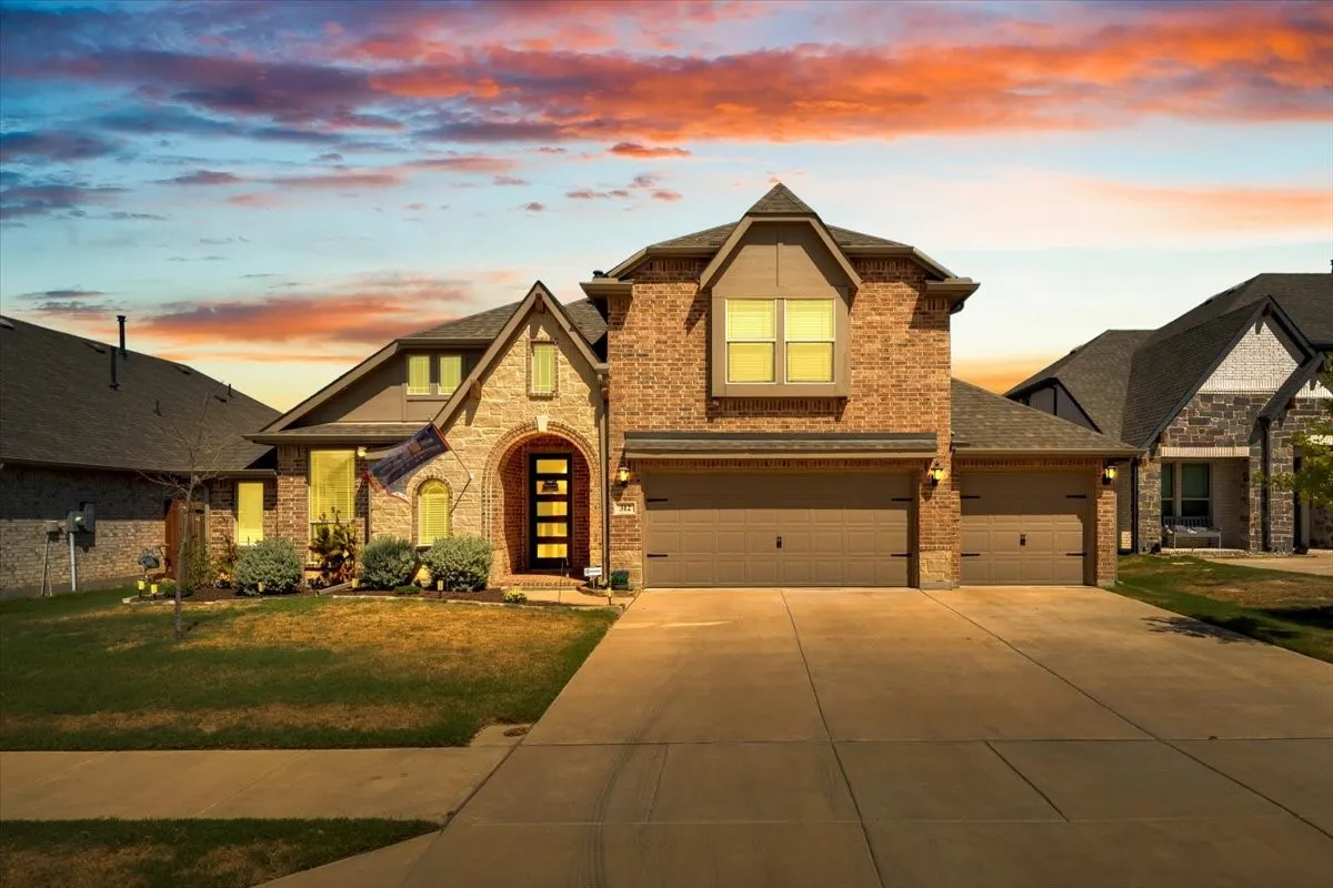 Brick and stone facade, arched entryway, multi-paneled front door, attached two-car garage, and concrete driveway
