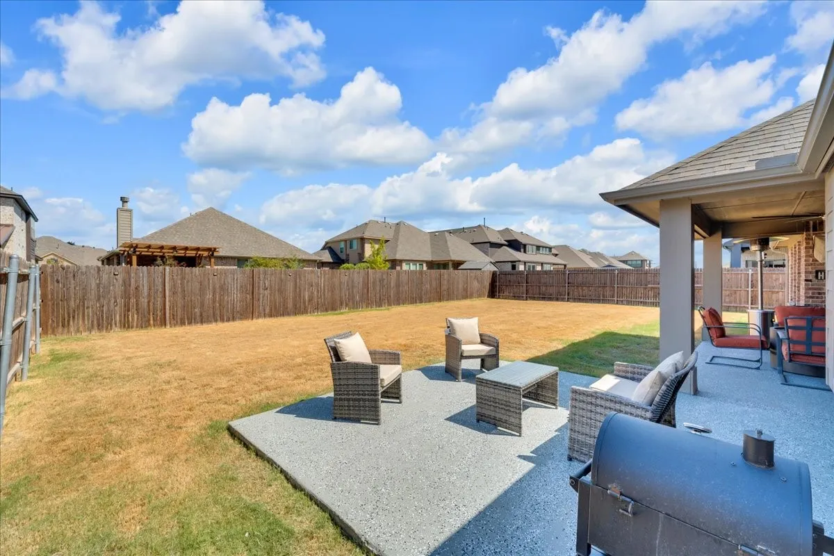 Expansive backyard featuring a full privacy fence, covered patio, and additional paved patio space
