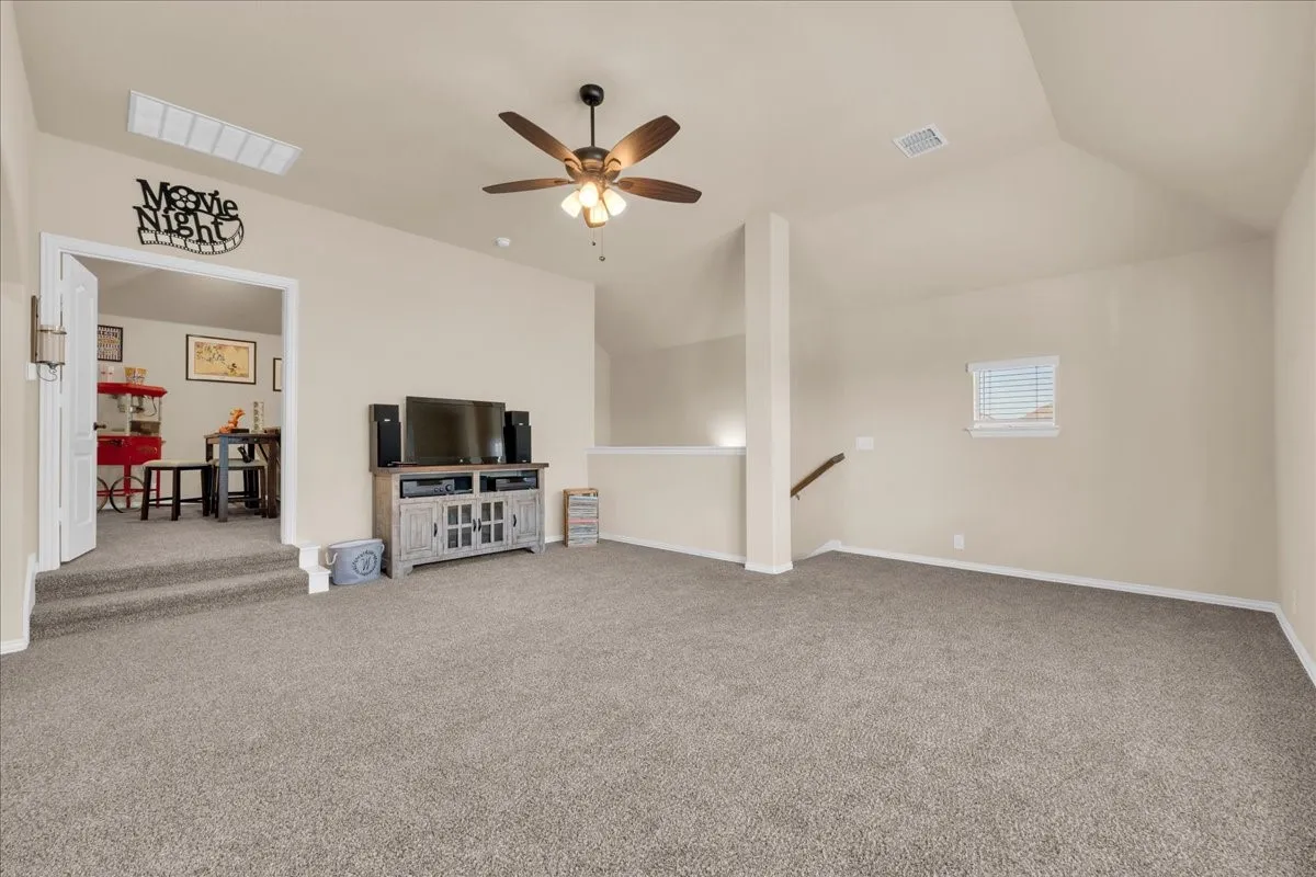 Spacious bonus room featuring vaulted ceilings, a ceiling fan with integrated lighting, and neutral carpeting