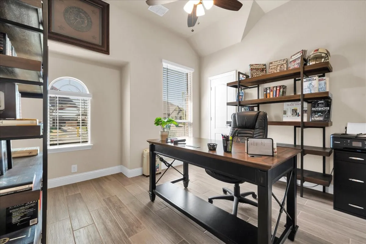 Vaulted ceiling with a ceiling fan, wood-finish flooring, and arched window