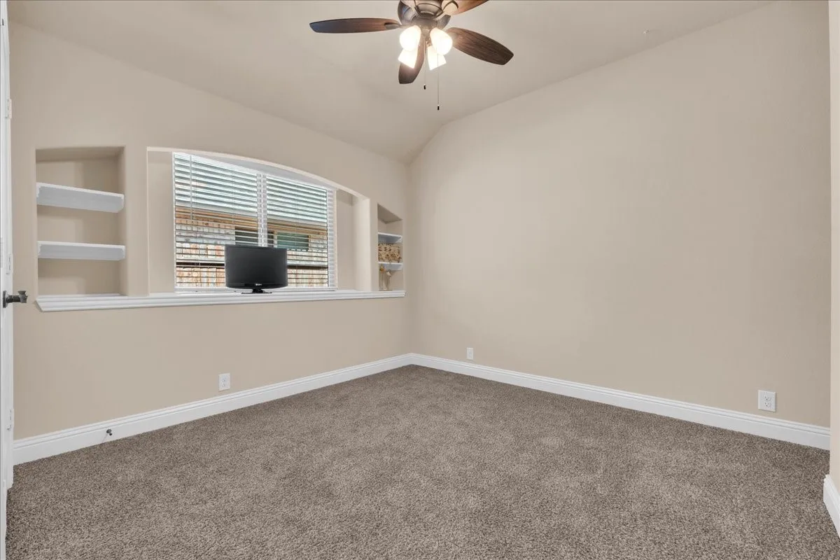 2nd Floor Bedroom with Arched window with built-in shelving, vaulted ceiling, ceiling fan, and carpeted flooring