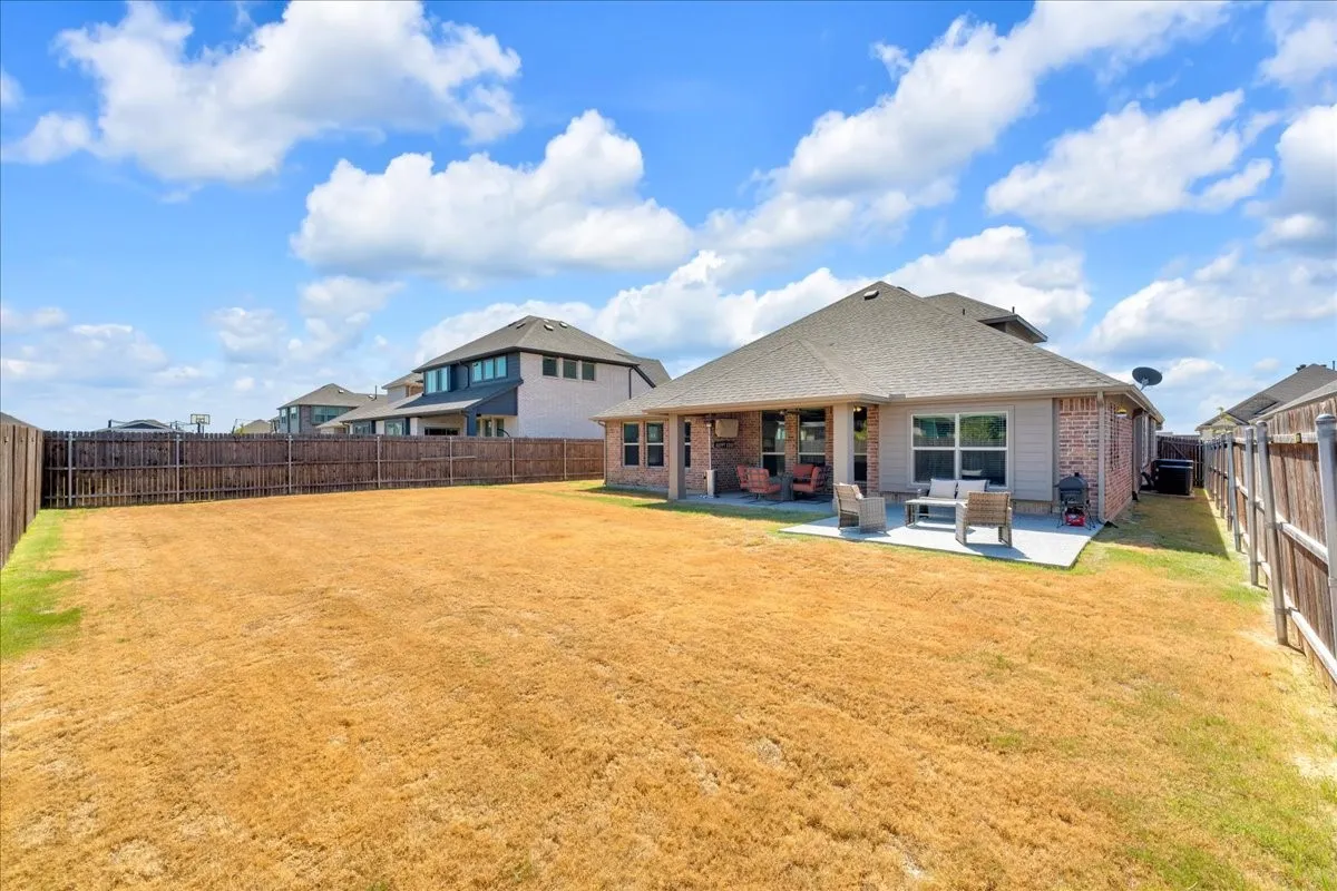 Expansive backyard with a wood privacy fence, concrete patio, and covered patio area