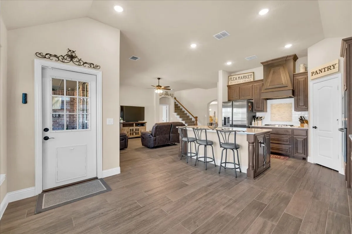 Kitchen featuring dark wood cabinetry, a central island with seating, stainless steel appliances, and wood-look tile flooring
