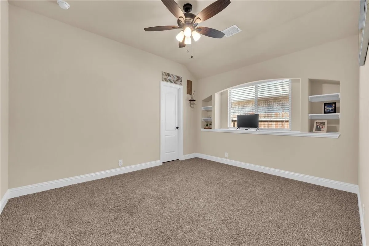 2nd Floor Bedroom with Vaulted ceiling with a ceiling fan, arched window with integrated blinds, and built-in wall shelving