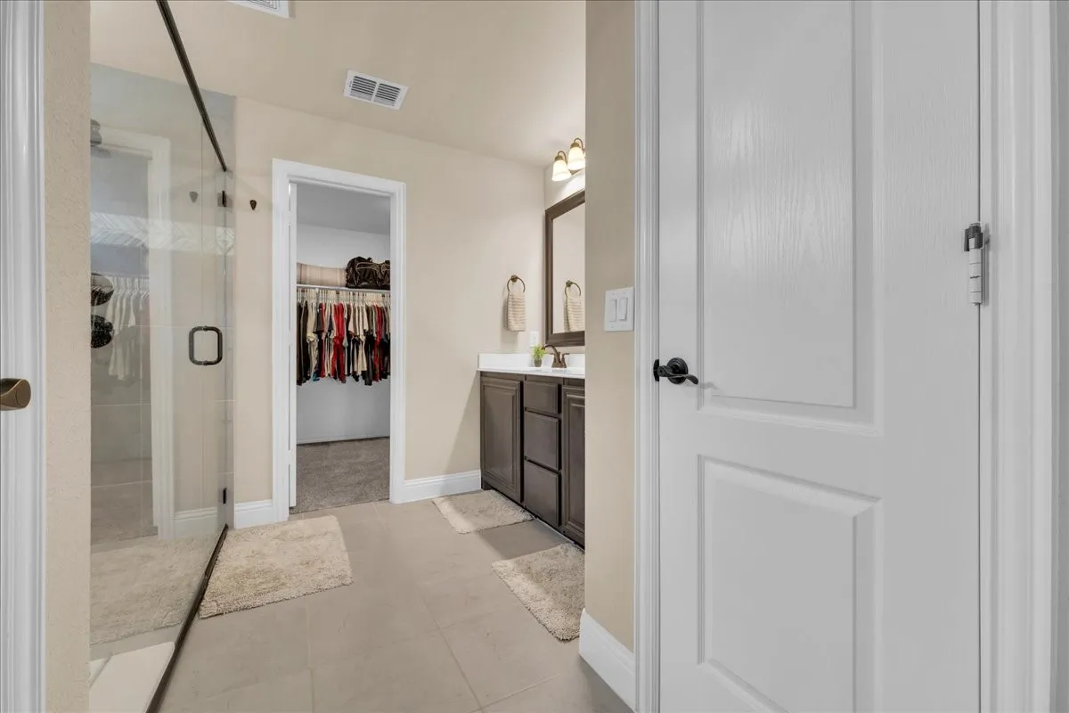 Bathroom featuring a glass-enclosed shower, dark wood-finish vanity, and a framed mirror