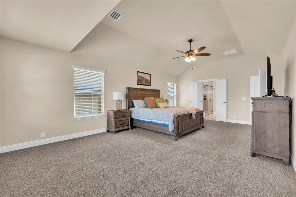 Vaulted ceilings with a ceiling fan, carpeted flooring, and a window with blinds