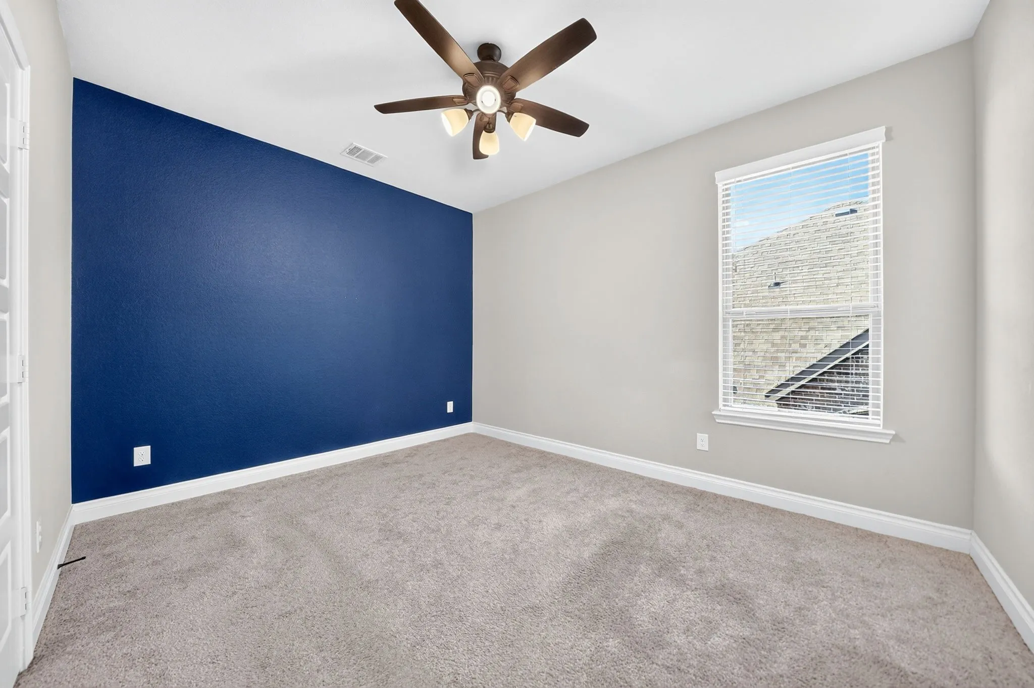 Carpeted flooring, single window with blinds, ceiling fan with integrated lighting, accent wall, white trim