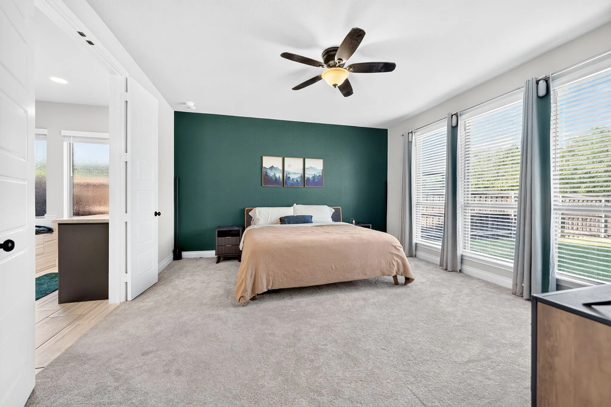 Spacious room with a dark green accent wall, light gray carpeting, and multiple large windows