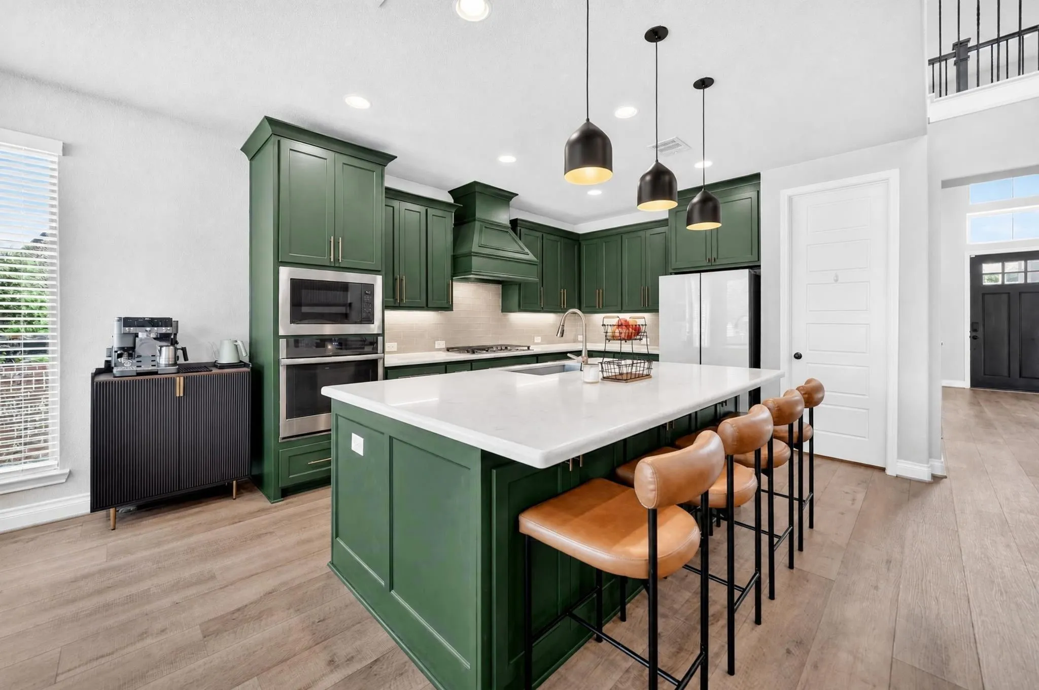 Kitchen featuring green cabinetry, stainless steel appliances, a white island countertop, wood-finish flooring, and pendant lighting