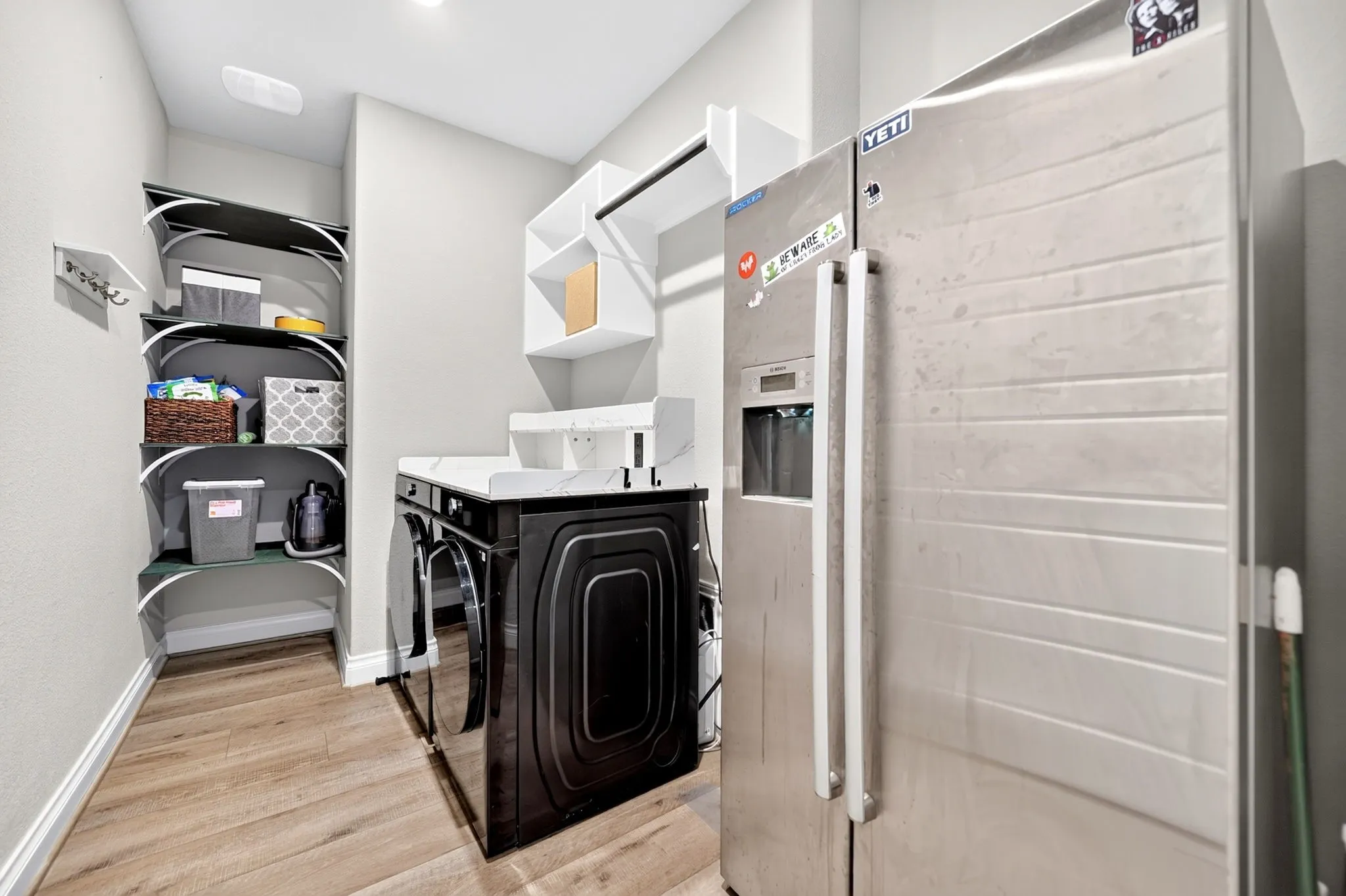 Wood-finish flooring, built-in shelving, countertop space, and overhead storage with a hanging rod