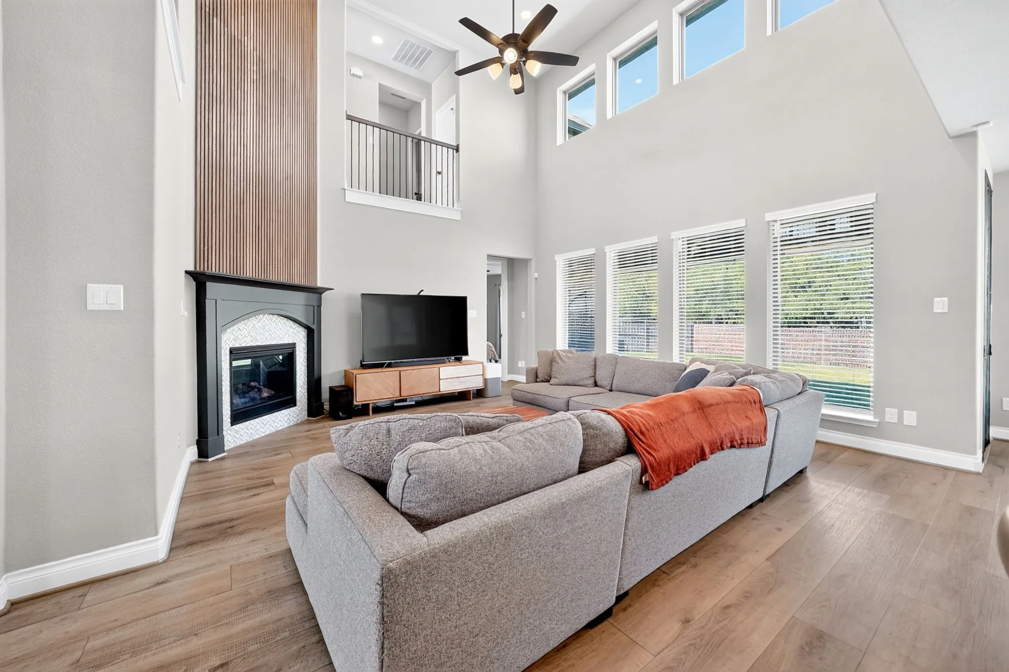 Two-story living area with high ceilings, wood-finish flooring, and a ceiling fan