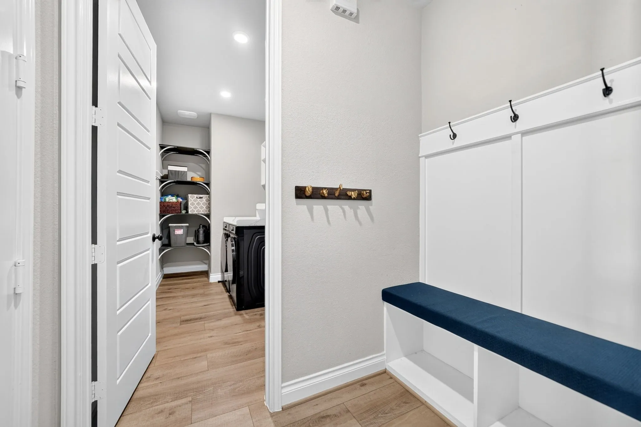 Built-in bench with storage, board and batten wall paneling, and wood-finish flooring