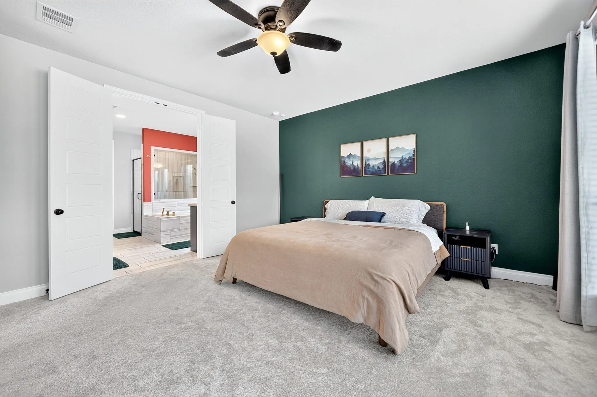 Carpeted flooring with a contrasting accent wall, ceiling fan, and double doors opening to a bathroom with a built-in tub and glass-enclosed shower