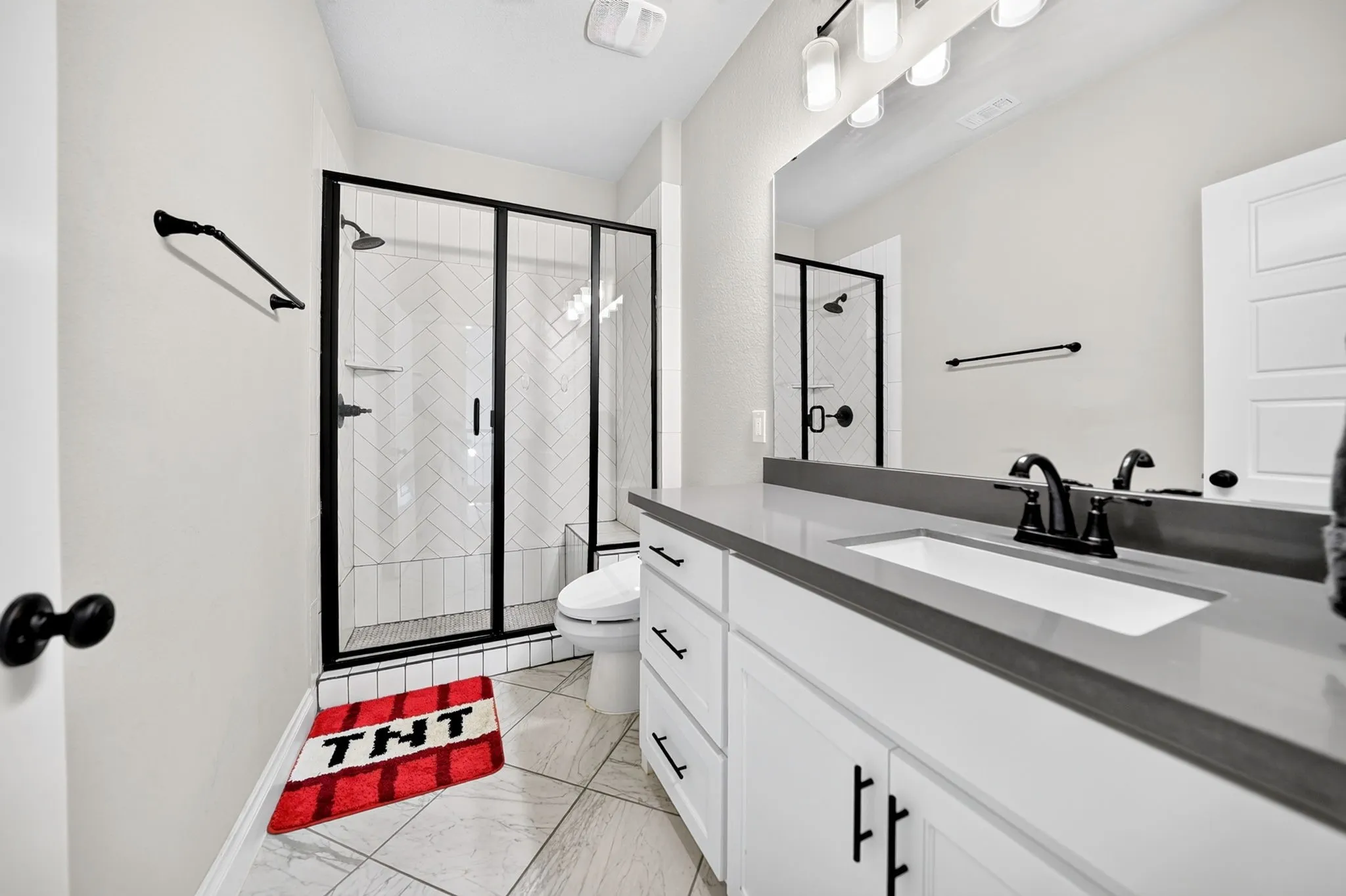 Single vanity with an integrated rectangular sink, dark countertop, and matte black faucet