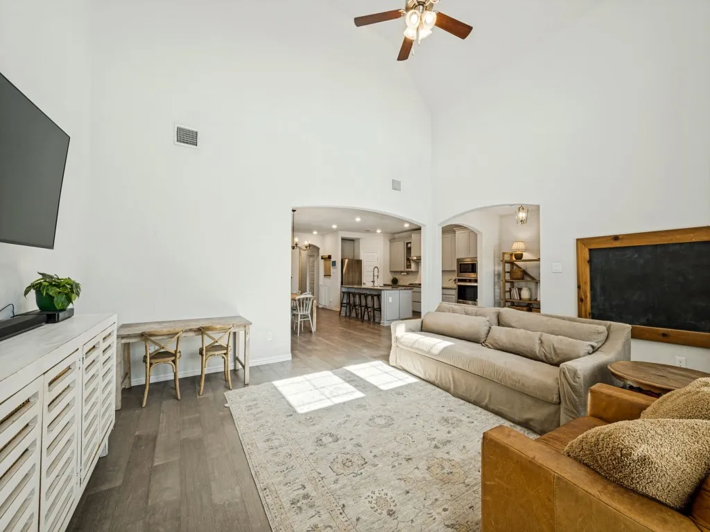 Vaulted ceiling with a ceiling fan, recessed lighting, wood-finish flooring, and arched doorways