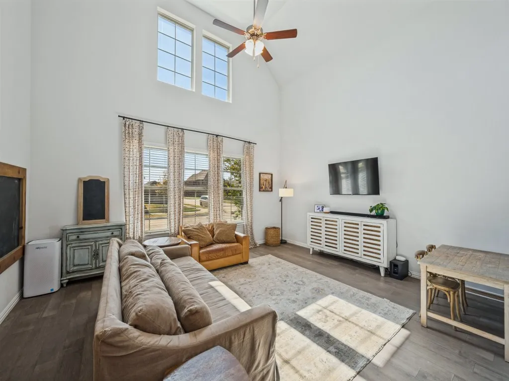 Vaulted ceilings, wood-finish flooring, ceiling fan, and a wall of windows