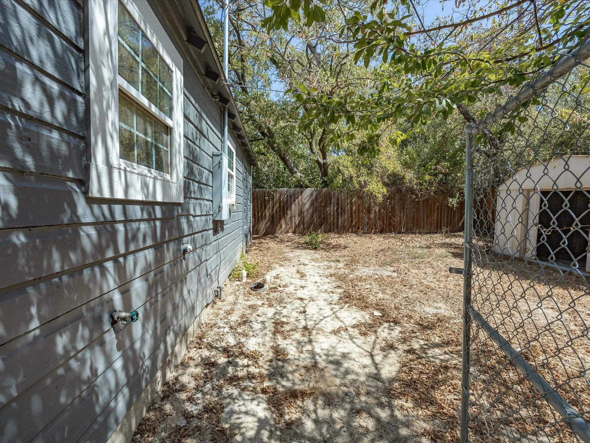Exterior featuring horizontal siding, multiple windows with white trim, a privacy fence, and an outdoor storage shed