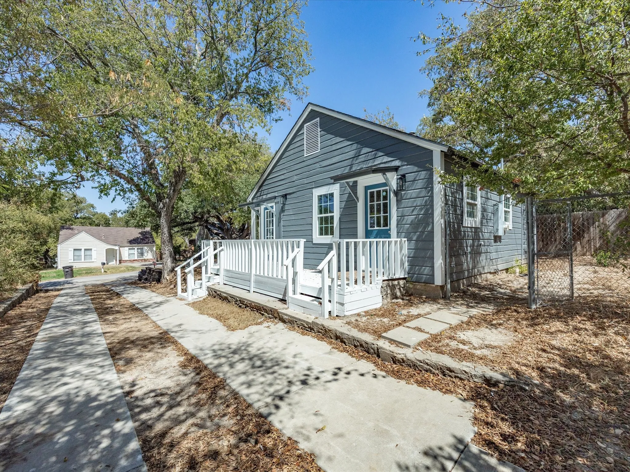 Siding exterior with a covered entry, white porch railing, and concrete walkway