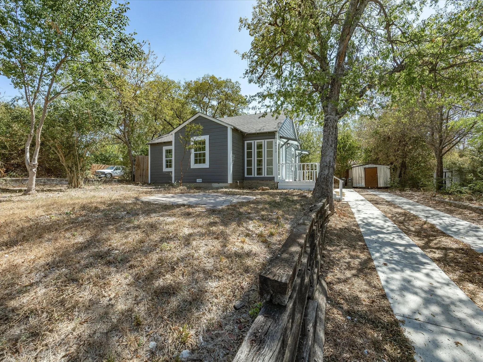 Gray siding exterior with white trim windows and a covered front porch featuring white railings