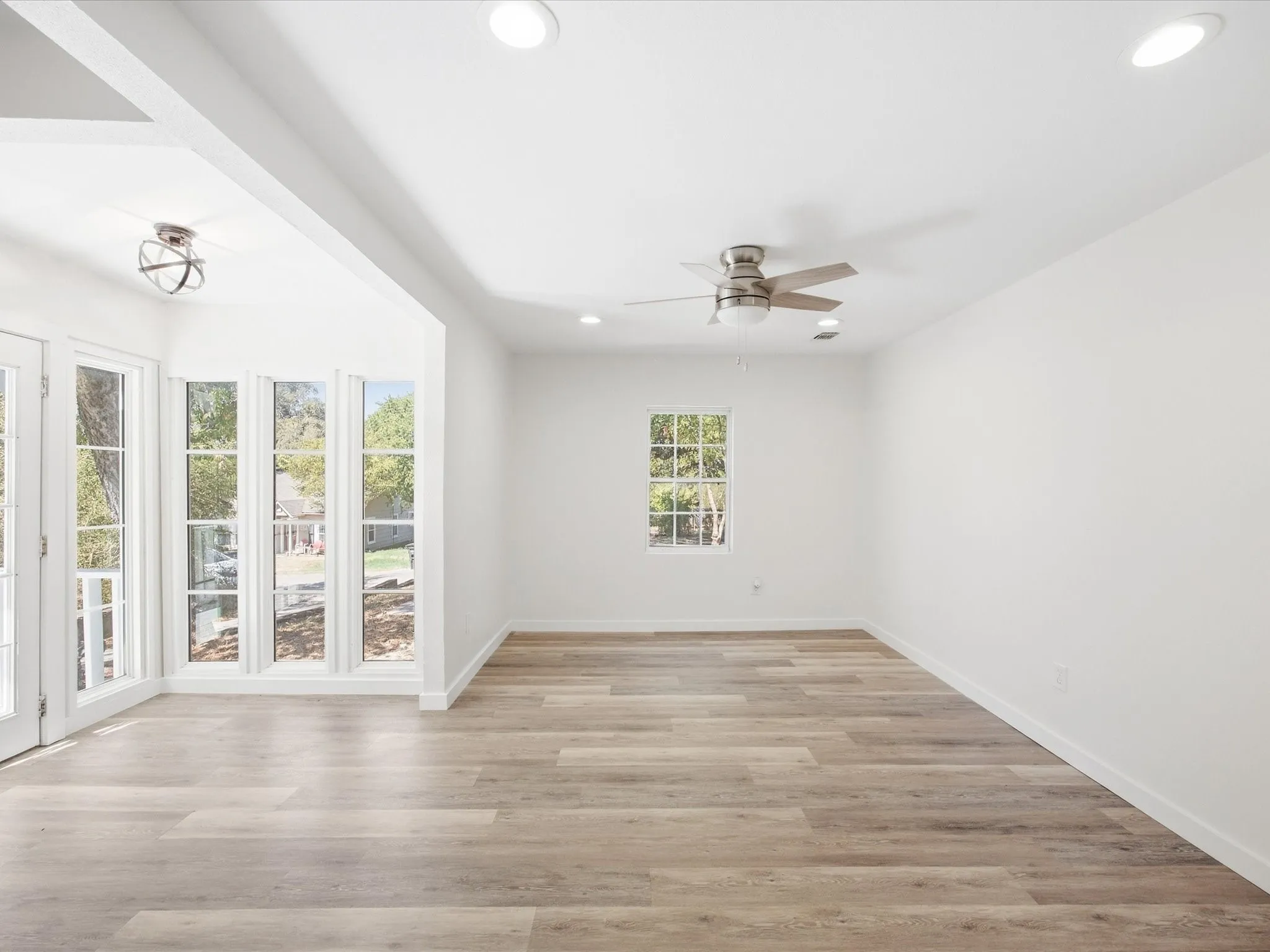 Spacious room featuring wood-finish flooring, recessed lighting, and a ceiling fan