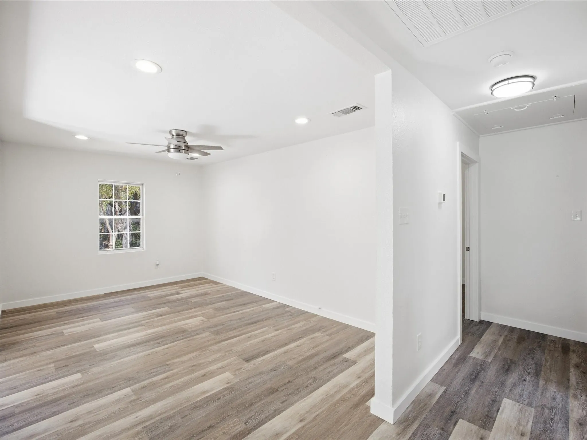 Wood-finish flooring, recessed lighting, ceiling fan, white walls, and a window with muntins