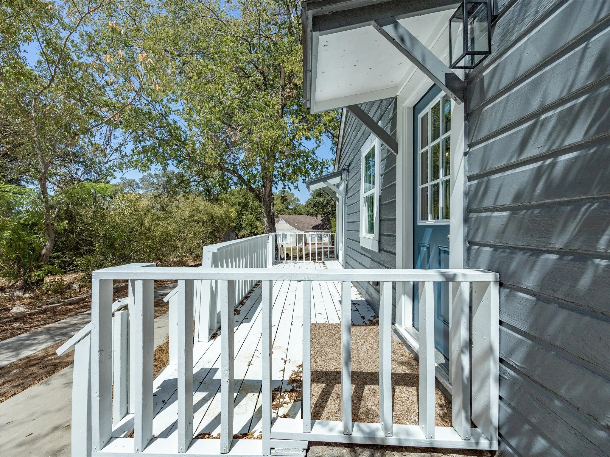 Exterior siding with a blue entry door, white trim, and a black wall-mounted lantern