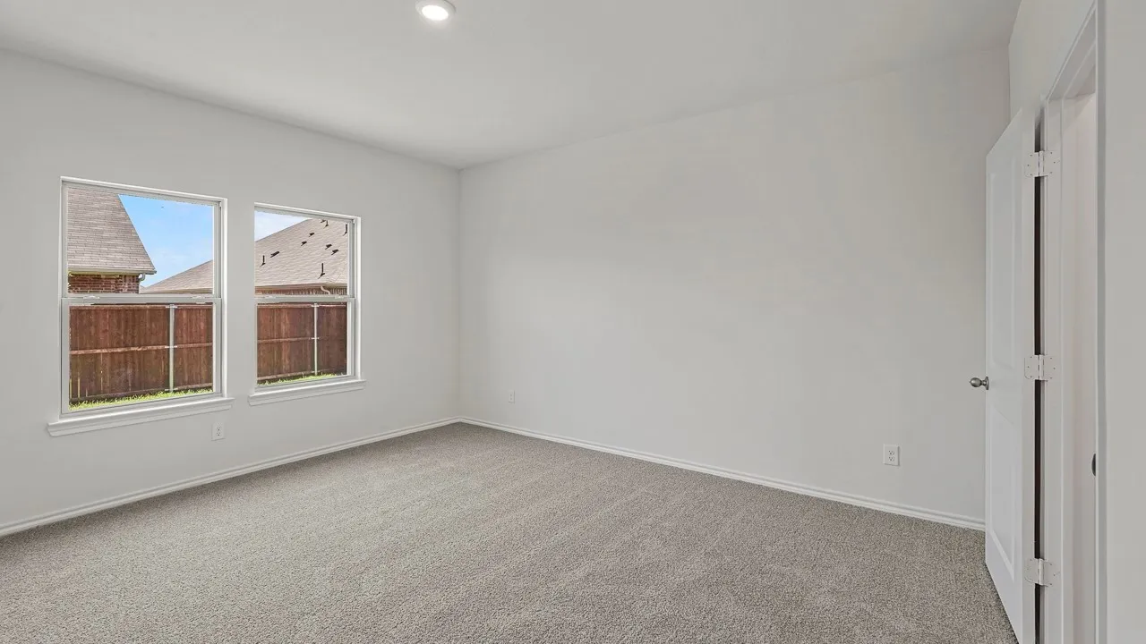 Carpeted room featuring two windows, recessed lighting, and a white interior door