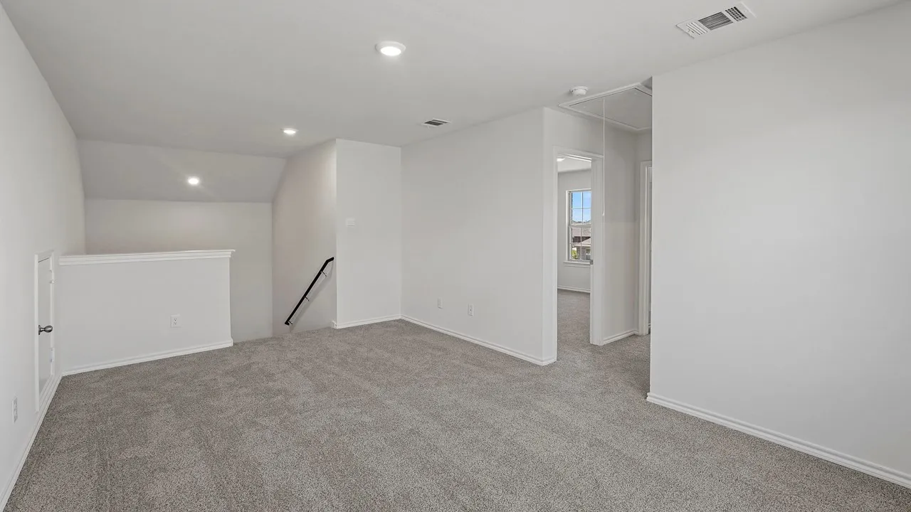 Carpeted room featuring a white painted railing, recessed lighting, and a doorway