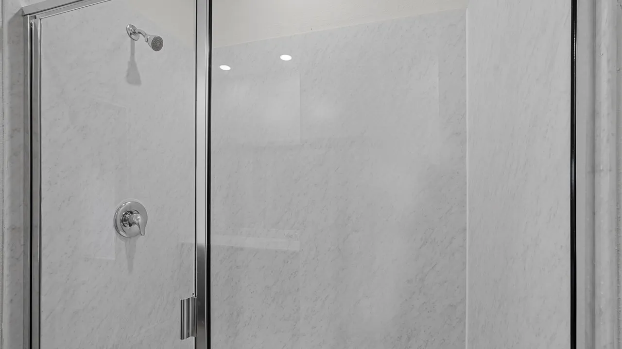 Shower enclosure featuring clear glass panels, chrome hardware, and light-toned wall surround