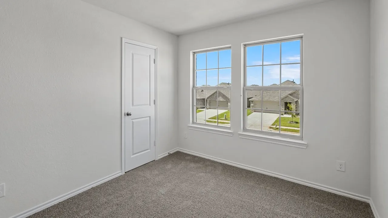 Two large windows with grid inserts, light neutral-toned wall paint, white trim, and gray carpet flooring