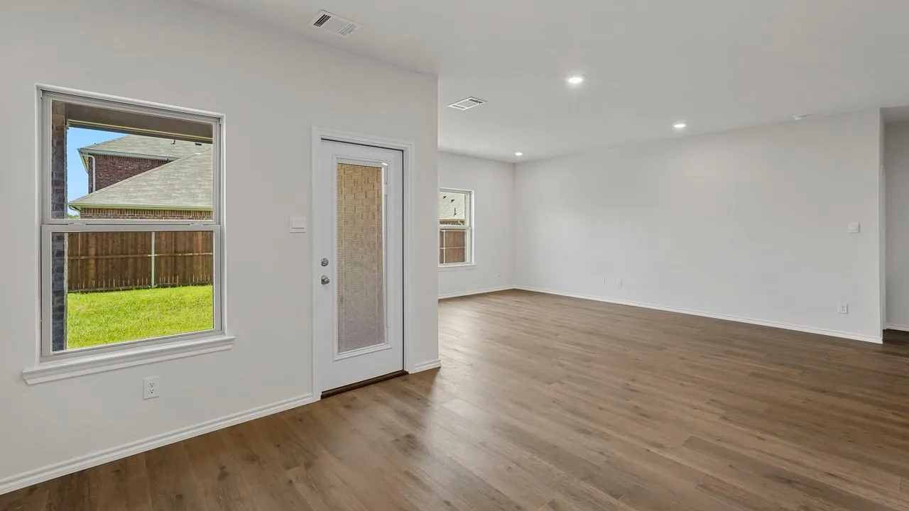 Expansive room featuring wood-finish flooring, recessed lighting, and a glass-paneled exterior door