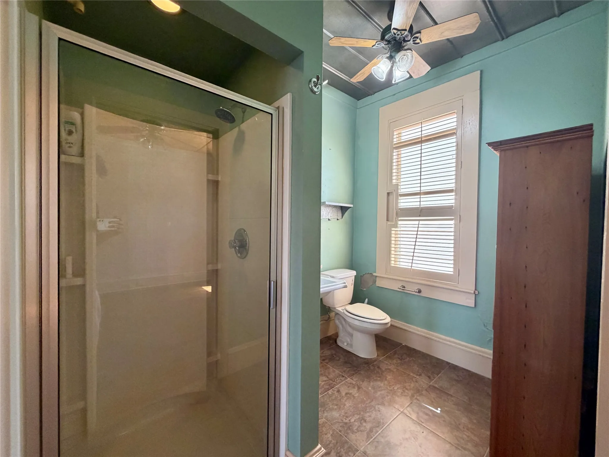 Glass-enclosed shower with a chrome fixture