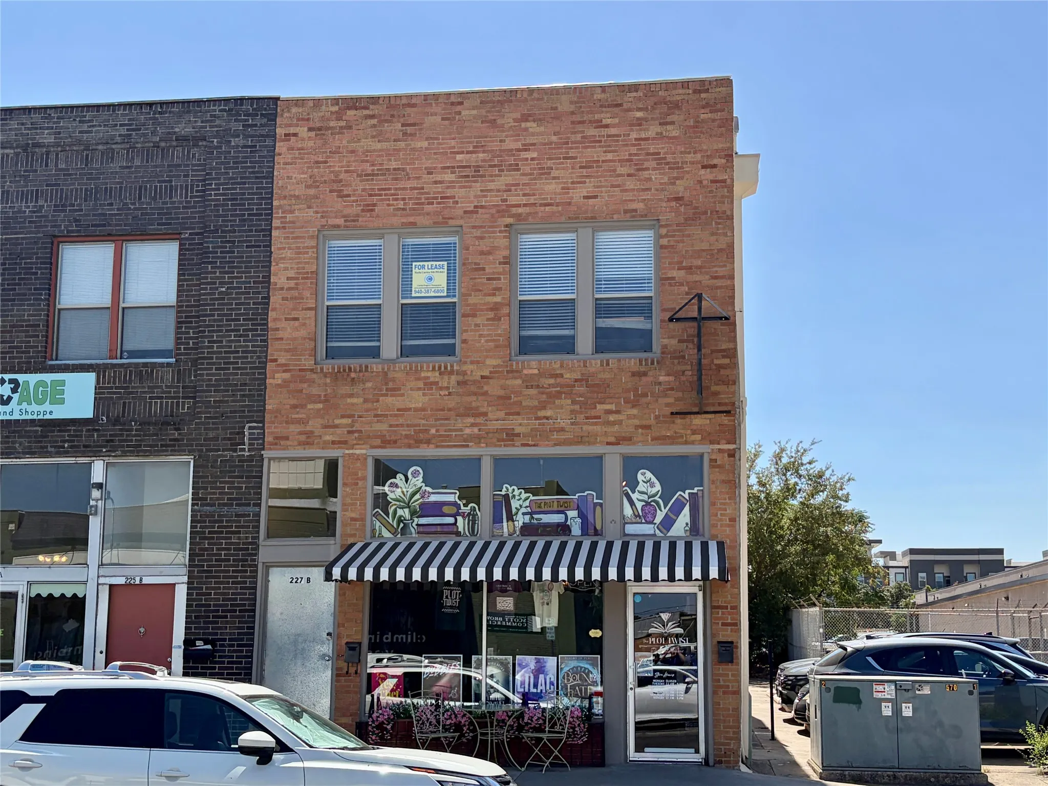 Two-story brick facade with a striped awning and ground-level retail windows
