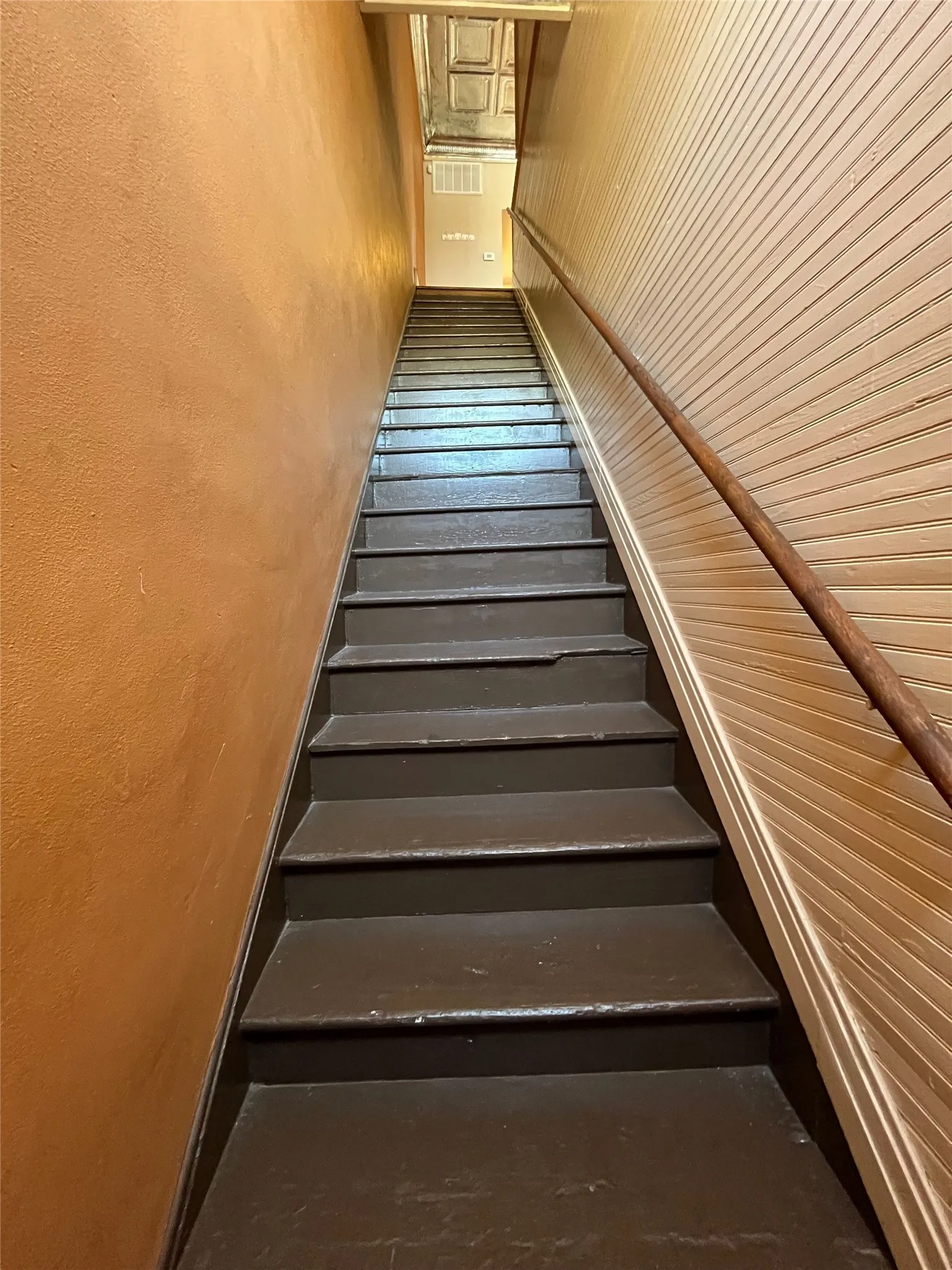 Staircase with painted treads and risers, textured wall, and wood paneling