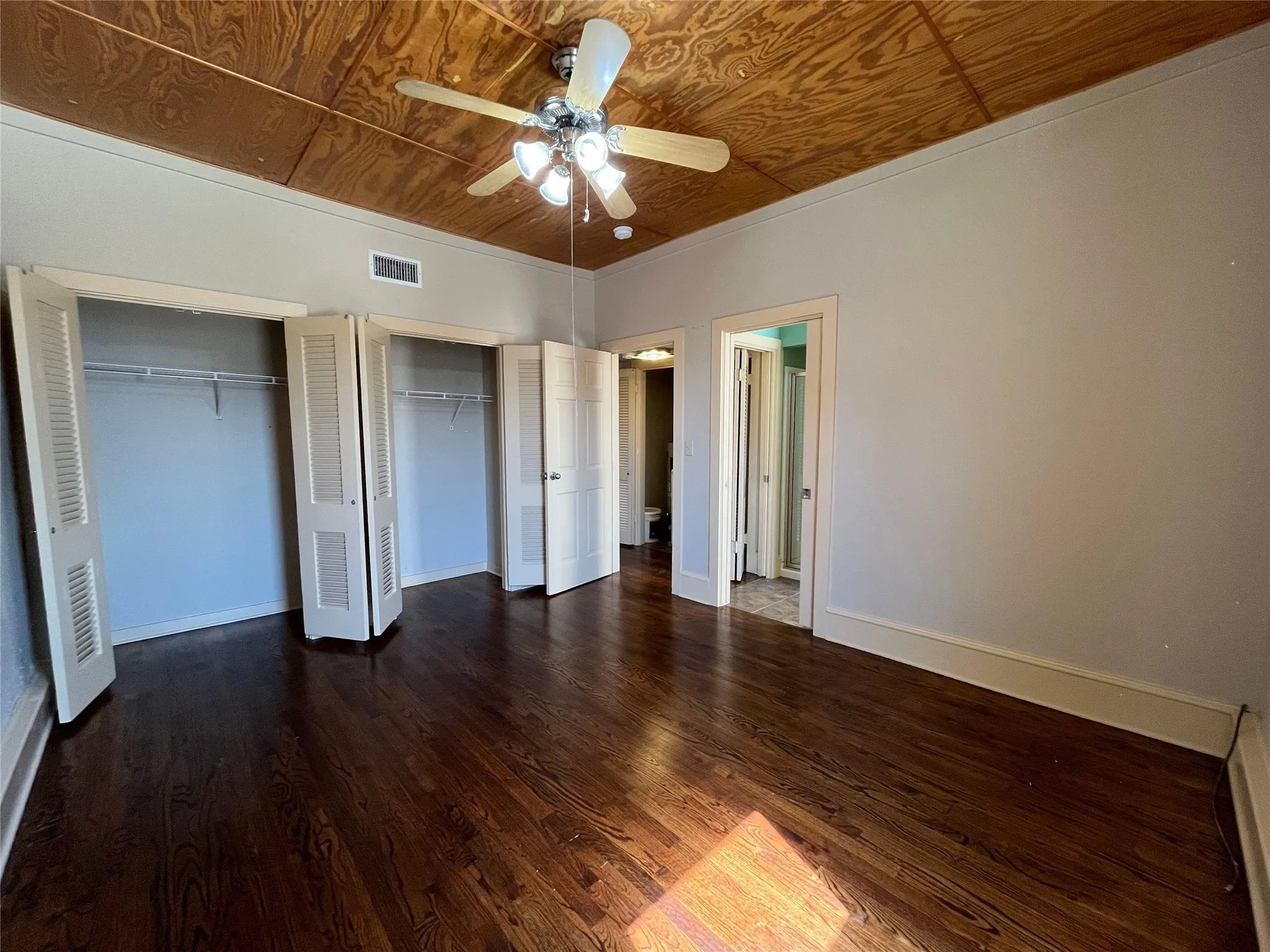 Hardwood flooring, wood-finish ceiling, bi-fold louvered closet doors, ceiling fan with integrated lighting, and crown molding