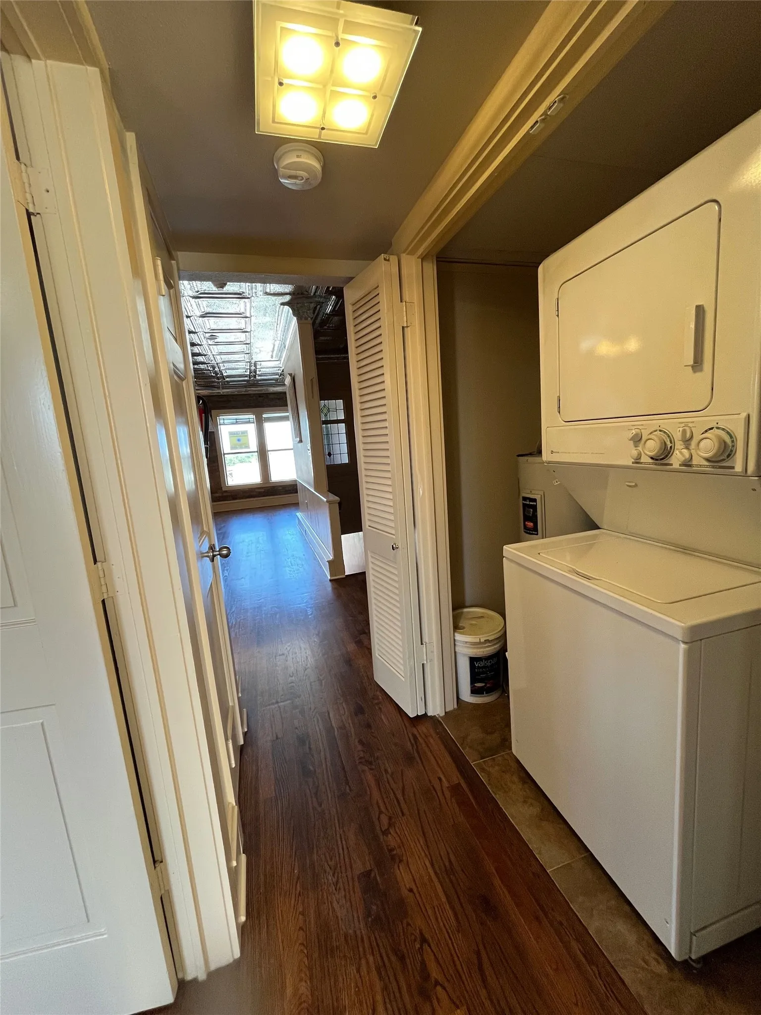 Hardwood-finish flooring, built-in stacked washer and dryer, ceiling-mounted light fixture, white interior doors, and louvered bi-fold door