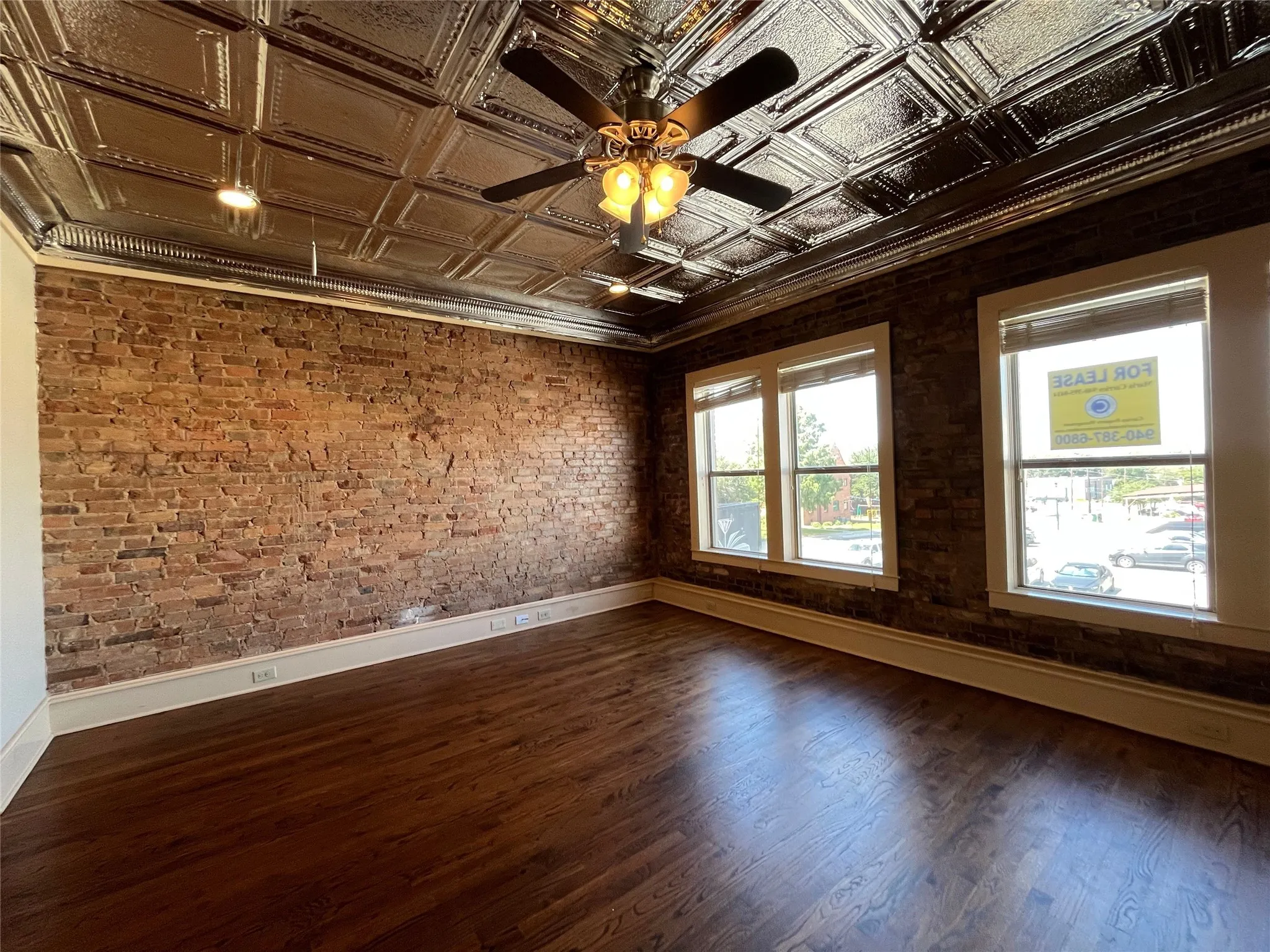 Exposed brick walls, dark wood-finish flooring, and a decorative ceiling with recessed lighting