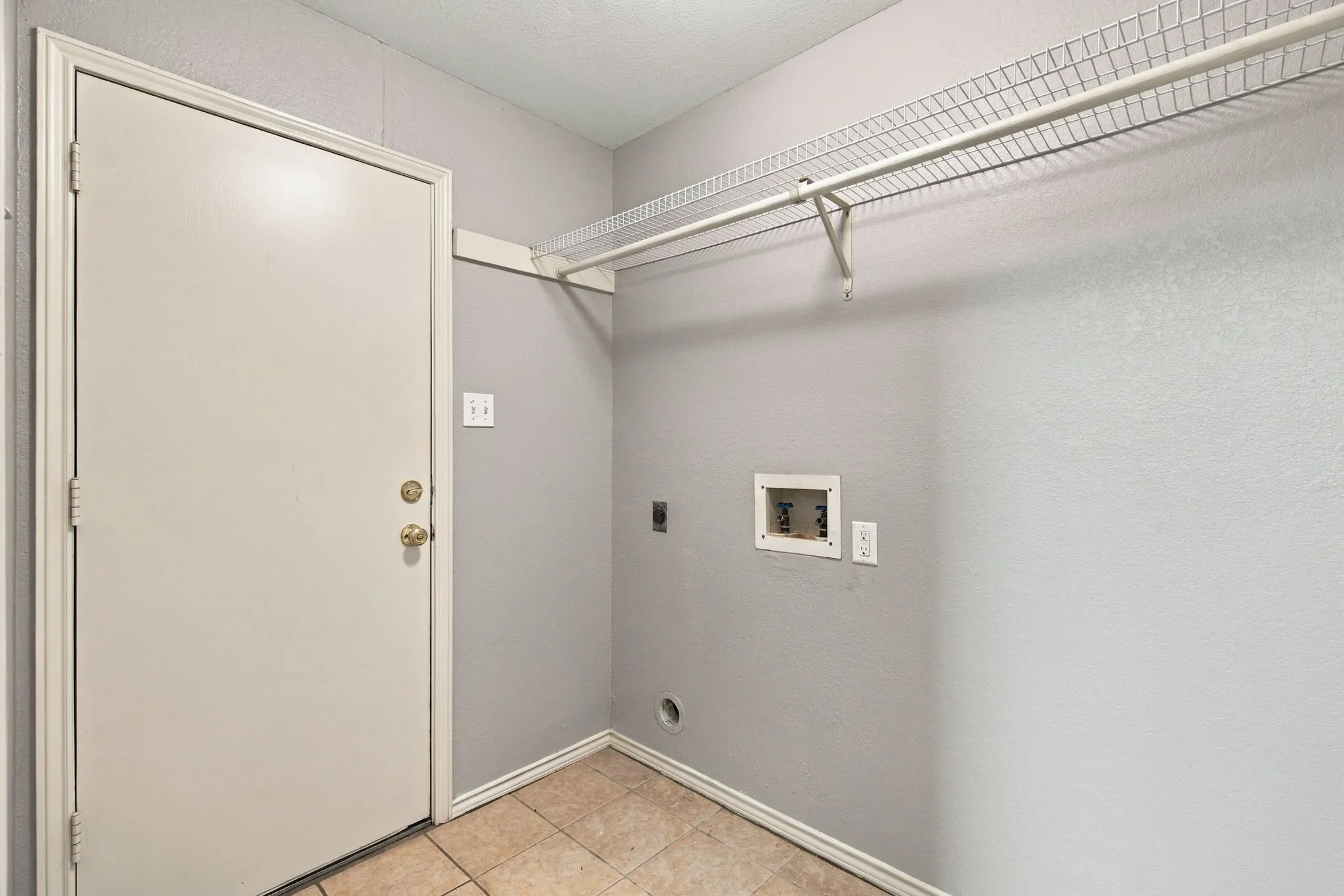 Utility area with neutral wall color, tile flooring, and a wire shelving unit