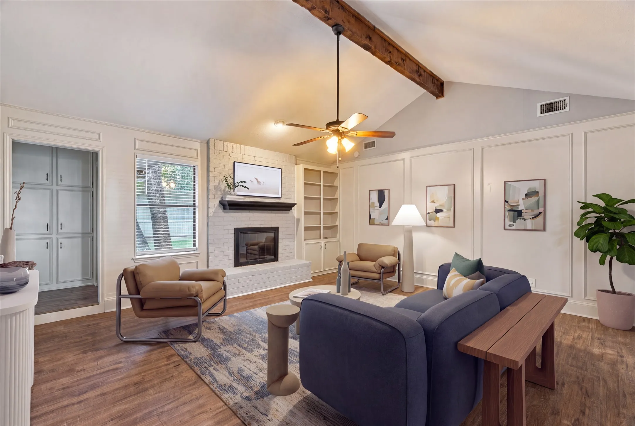 Vaulted ceiling with exposed wood beam, wood-finish flooring, brick fireplace with mantel, built-in shelving (Virtually staged)