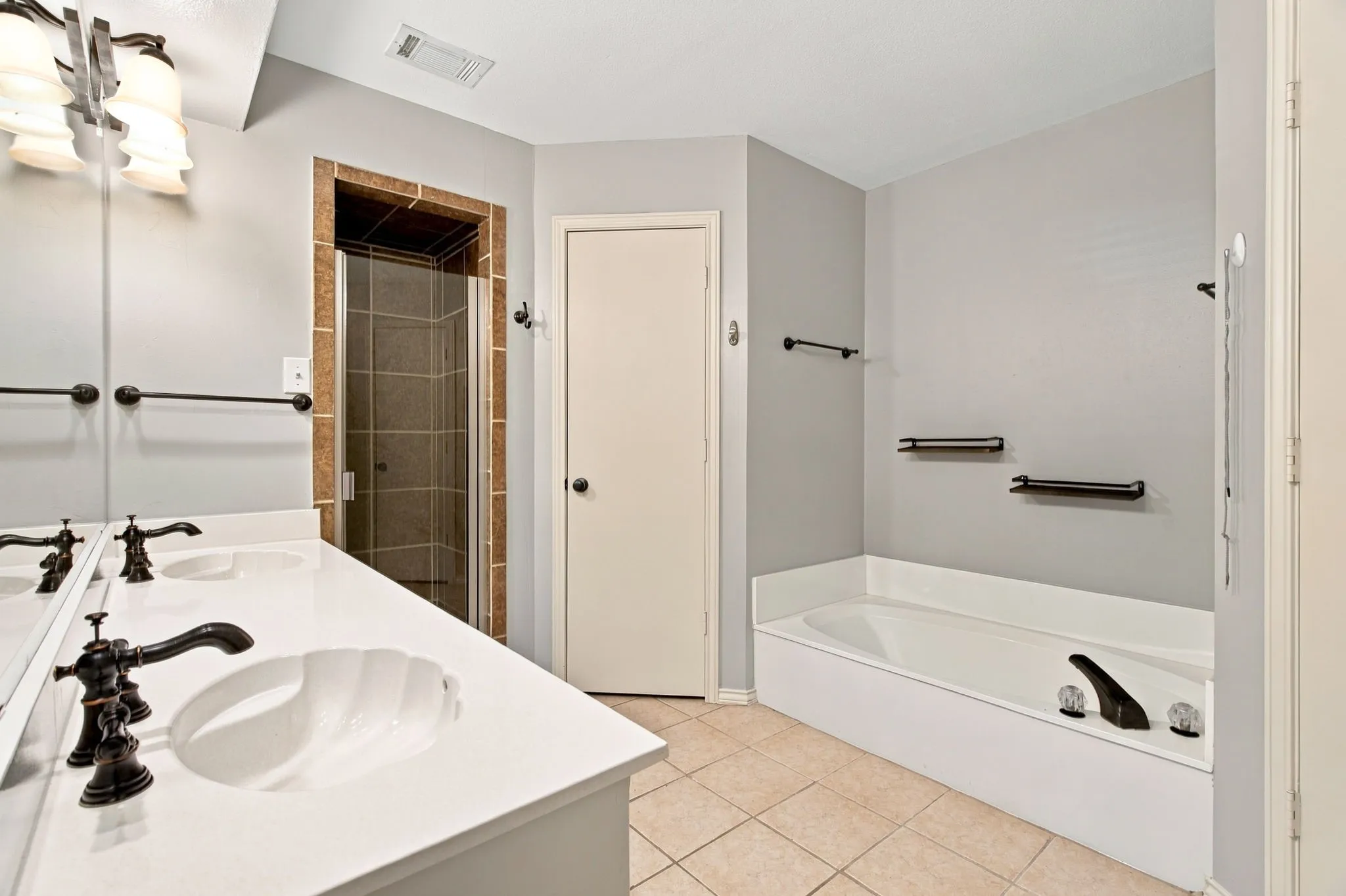 Double vanity with white countertops, bronze-finish faucets, and under-mount sinks