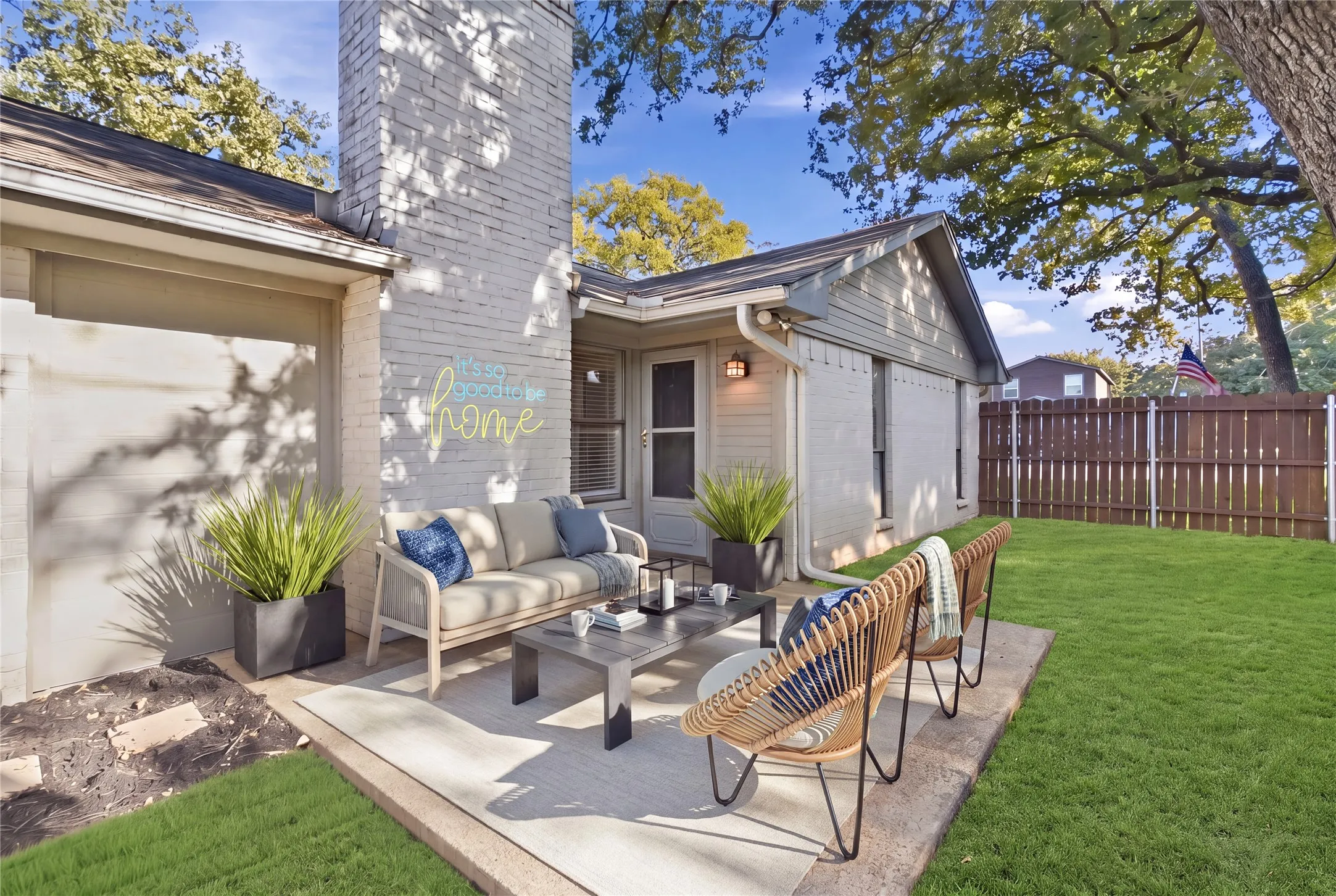 Patio area with a brick chimney, fencing, and a grassed yard (Virtually staged)