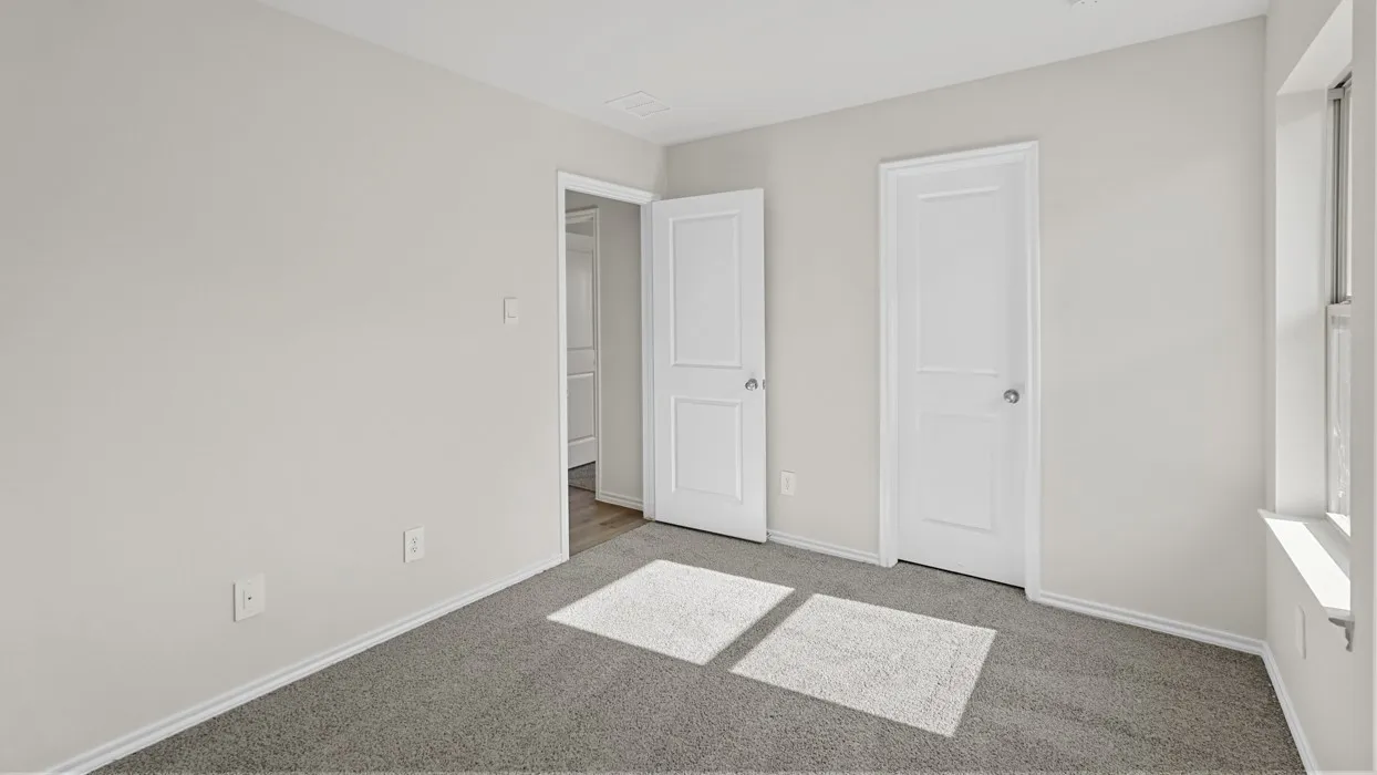 Light gray walls with white trim, gray carpet flooring, and two white panel doors