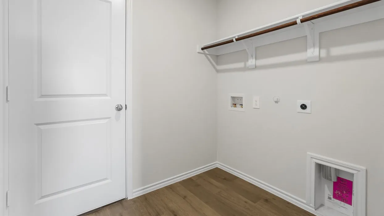 Laundry area featuring wood-finish flooring, white walls, and a built-in hanging rod with shelving